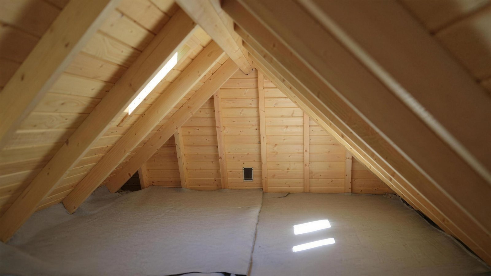 Sunlight through a roof vent into a clean, well-kept attic with exposed rafters